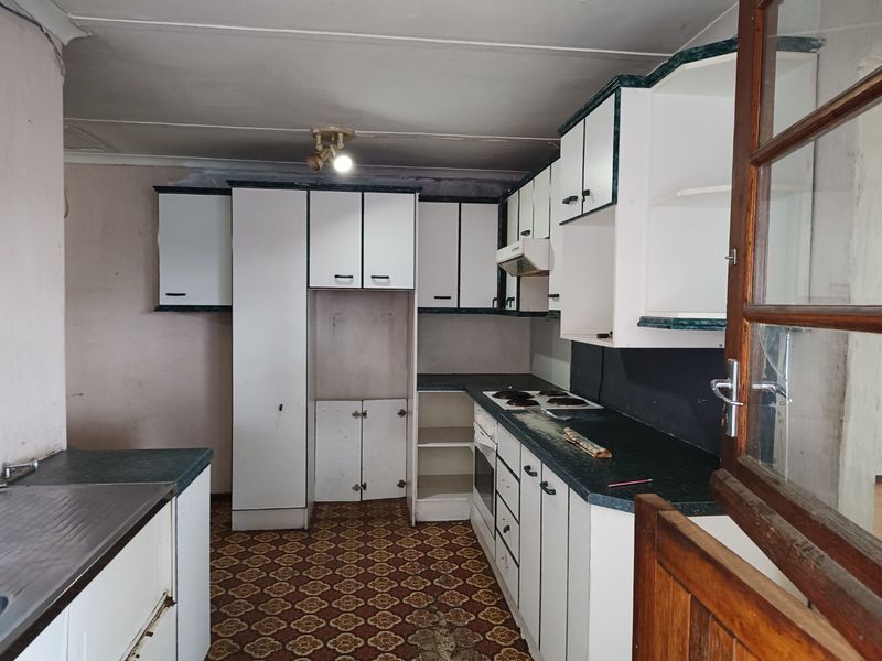 A dated kitchen featuring built-in cabinetry, an electric hob, and an oven, requiring significant renovation and modernization to reach its full potential.