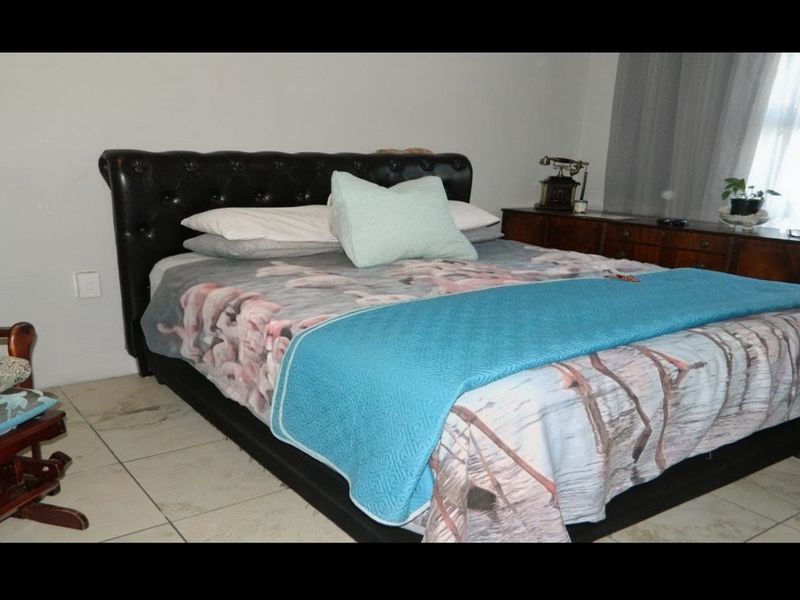 A bedroom featuring tiled flooring, which shows visible signs of cracking and wear, requiring maintenance or replacement.