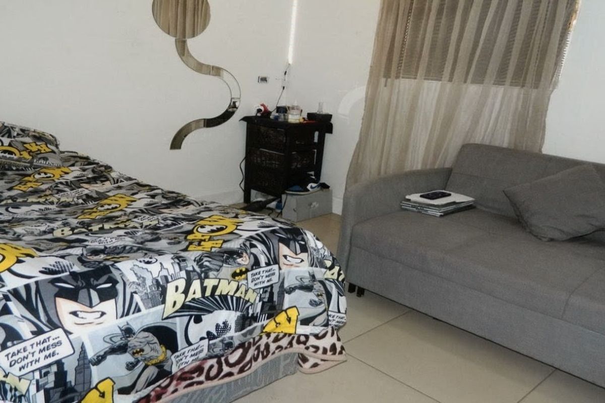 A bedroom featuring tiled flooring and a window with curtains, providing a functional living space.