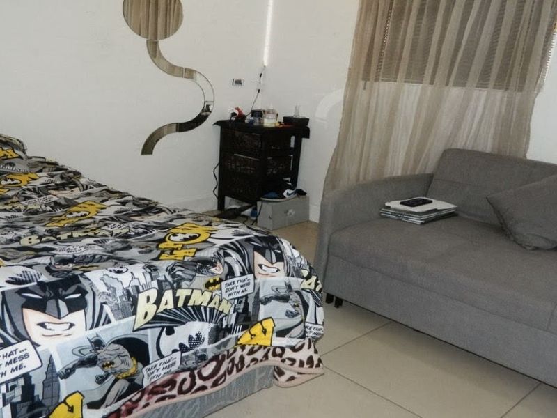 A bedroom featuring tiled flooring and a window with curtains, providing a functional living space.