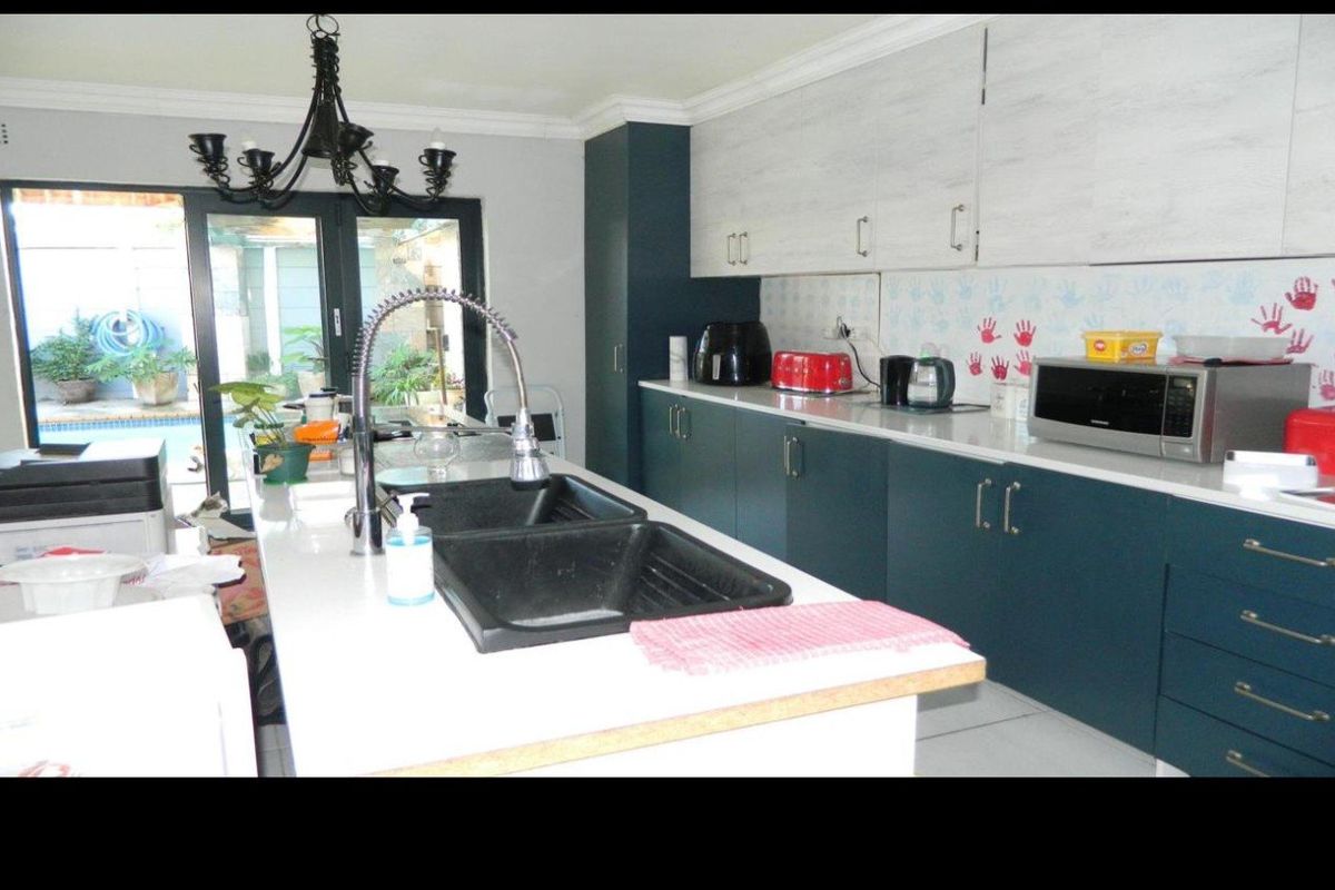Modern kitchen featuring a central island with a double basin sink, stone countertops, two-tone cabinetry, and direct access to the outdoor patio area.