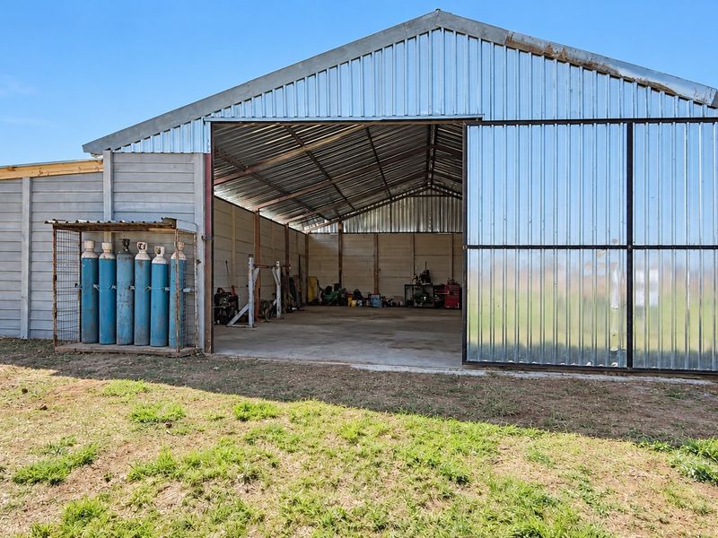 Large industrial-style farm shed featuring corrugated metal construction, a concrete floor, and a wide sliding door, suitable for workshop or storage use.