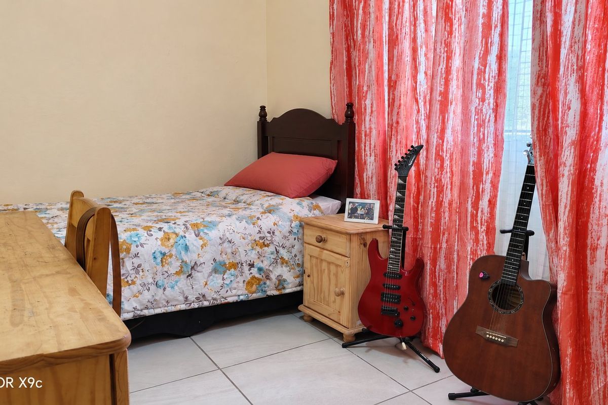 A functional bedroom featuring tiled flooring and neutral wall finishes, providing a comfortable space for rest.