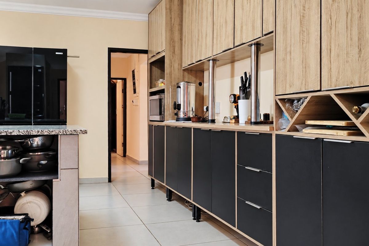 Modern kitchen featuring two-tone cabinetry, granite countertops, integrated microwave, and dedicated wine storage with clean tiled flooring.
