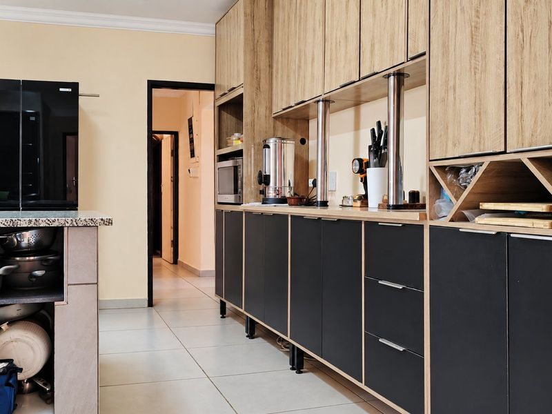 Modern kitchen featuring two-tone cabinetry, granite countertops, integrated microwave, and dedicated wine storage with clean tiled flooring.