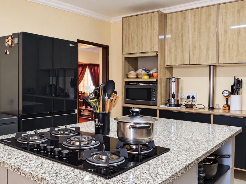 Modern kitchen featuring a large granite-topped island with a built-in gas cooktop, ample laminate cabinetry, and integrated microwave space.