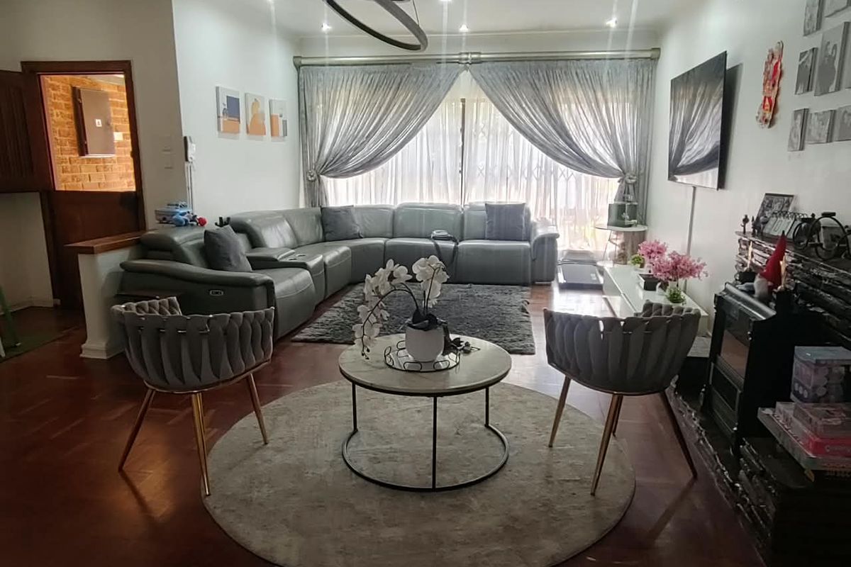 A comfortable living room featuring hardwood flooring, recessed lighting, and a fireplace, with large sliding doors providing access to the exterior.