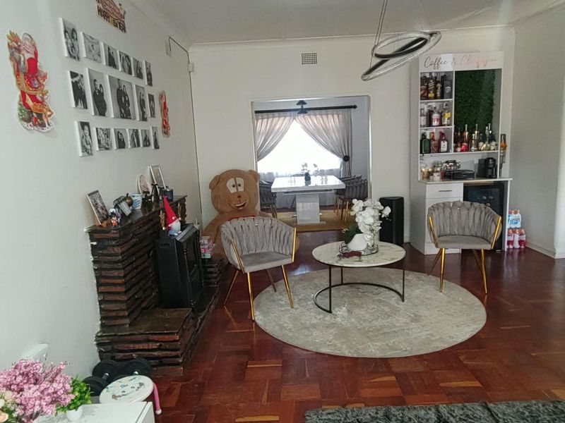 A living room featuring parquet flooring, a built-in fireplace, and a dedicated built-in bar area, with an open transition to the dining space.