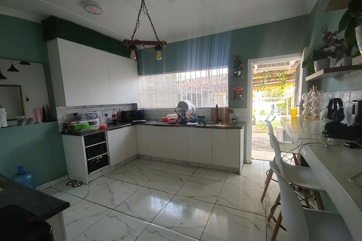 Modern kitchen featuring white cabinetry, dark countertops, subway tile backsplash, and marble-look floor tiles, with direct access to the outdoor patio area.