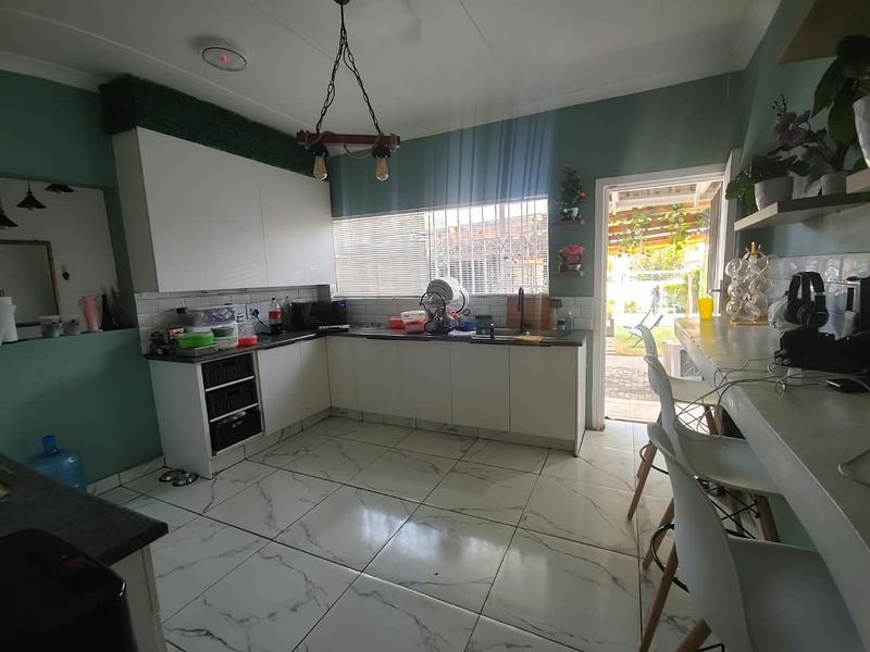 Modern kitchen featuring white cabinetry, dark countertops, subway tile backsplash, and marble-look floor tiles, with direct access to the outdoor patio area.