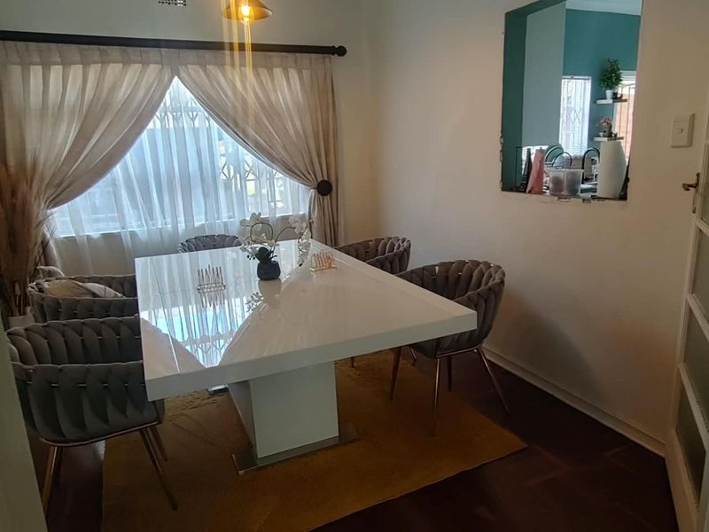 A well-maintained dining room featuring classic parquet flooring and a convenient serving hatch connecting to the kitchen area.