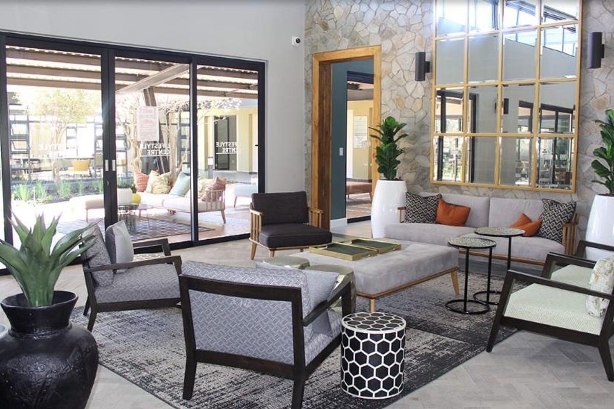 A modern, well-appointed living area featuring a striking stone feature wall, large sliding doors opening to a patio, and elegant herringbone flooring.