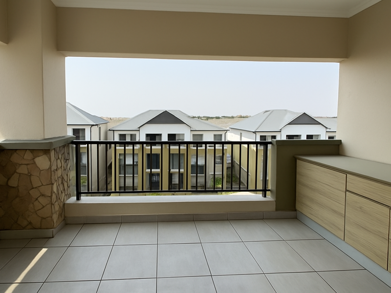 A covered balcony featuring tiled flooring, stone cladding accents, and built-in cabinetry, offering an open view of the surrounding residential complex.