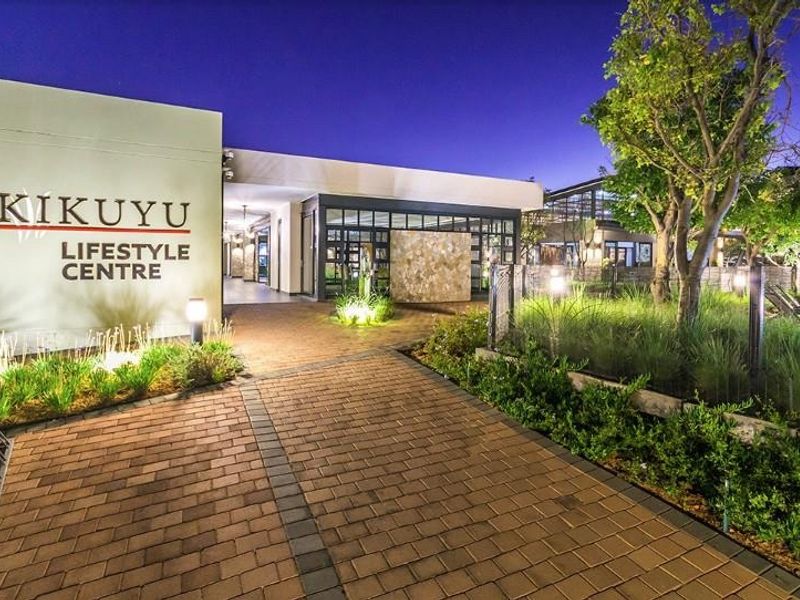 Exterior view of the Kikuyu Lifestyle Centre featuring a paved entrance walkway, landscaped gardens, and modern architectural stone cladding at dusk.