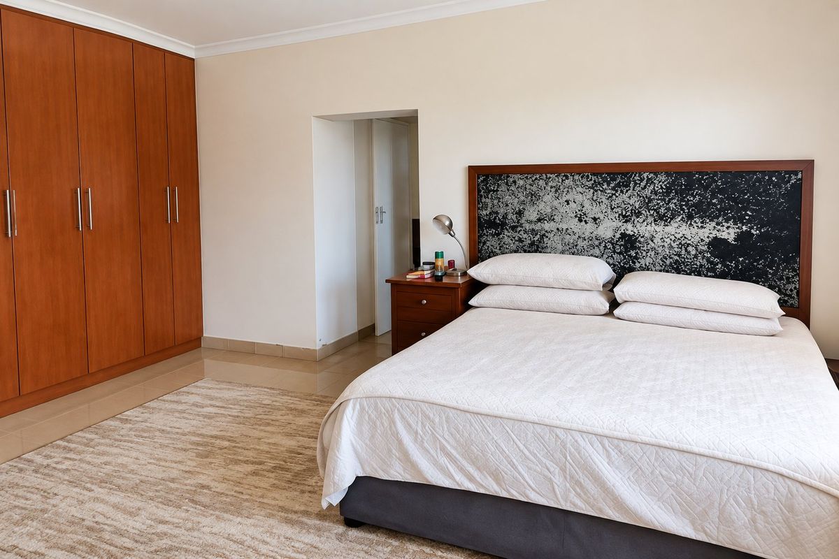 A well-maintained bedroom featuring built-in wooden cupboards, tiled flooring, and a neutral color palette, offering a clean and functional living space.