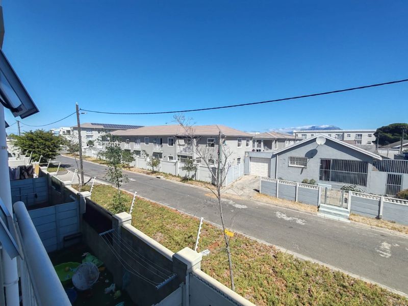 Elevated view overlooking the residential street, surrounding apartment complexes, and neighborhood infrastructure under a clear blue sky.