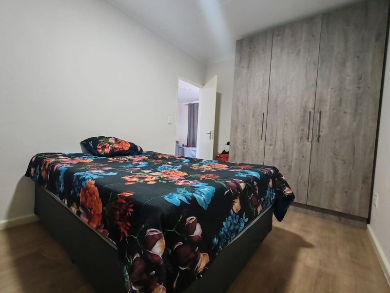 A well-maintained bedroom featuring modern wood-look built-in cupboards and durable laminate flooring, offering a clean and functional living space.
