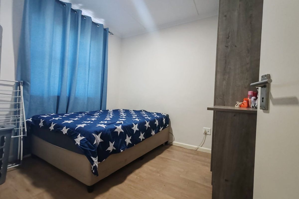 A functional bedroom featuring laminate flooring and a built-in cupboard, providing a clean and simple living space.