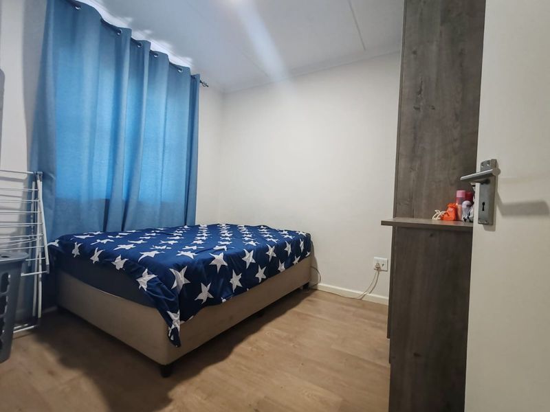 A functional bedroom featuring laminate flooring and a built-in cupboard, providing a clean and simple living space.