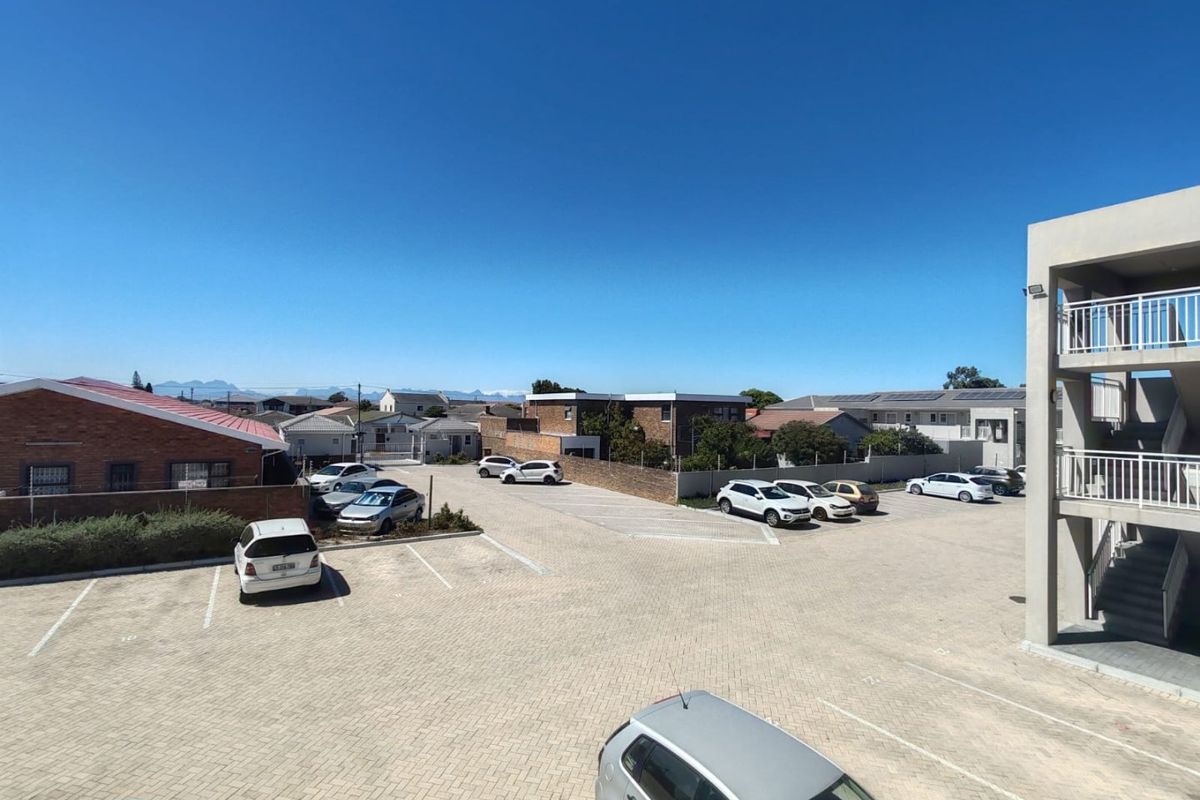 An elevated view overlooking a paved parking area and surrounding residential neighborhood with mountain views in the distance.