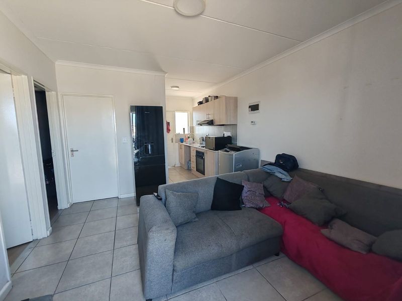 Open-plan living area featuring tiled flooring and a functional kitchen with built-in cabinetry, oven, and extractor fan.