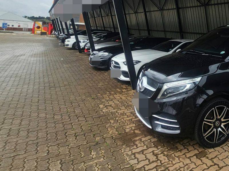 Commercial property featuring a paved outdoor parking area with a covered structure for vehicle protection.