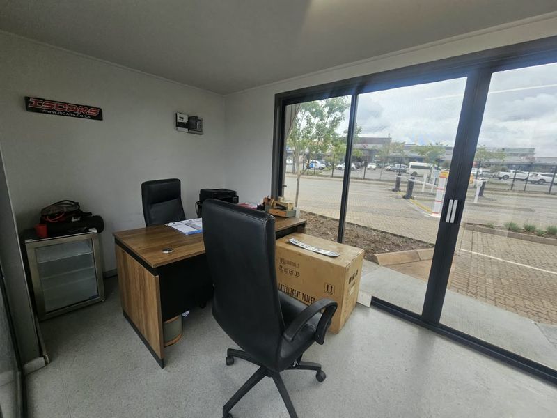 A functional commercial office space featuring large sliding glass doors that provide natural light and views of the exterior parking area.