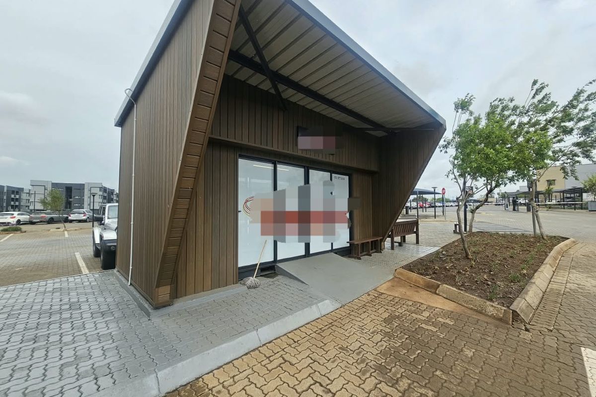 Modern commercial unit featuring timber cladding, a prominent metal roof overhang, glass storefront entrance, and an accessible concrete ramp.