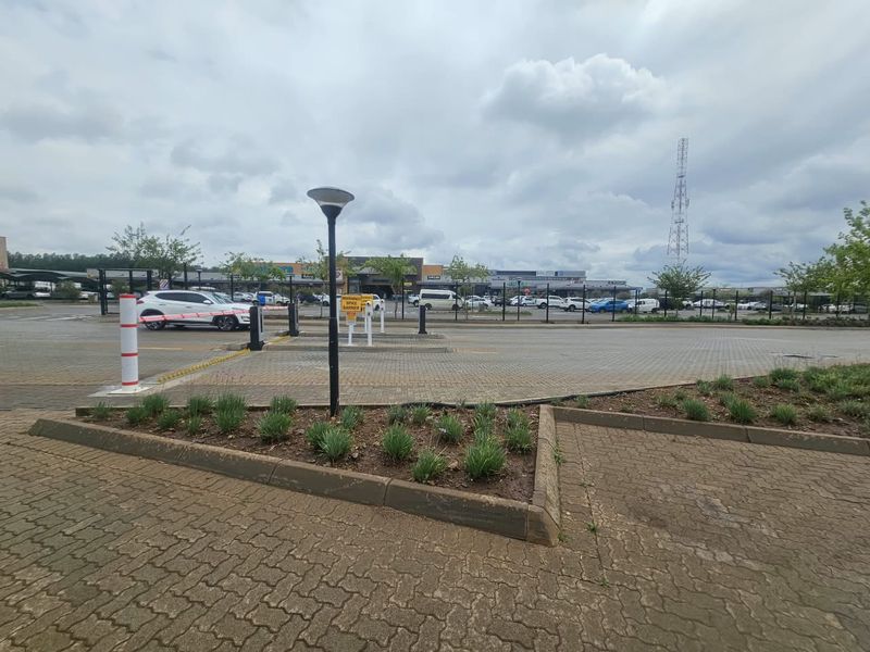 Commercial property entrance featuring a paved driveway, security boom gate with spike barrier, and landscaped garden beds.