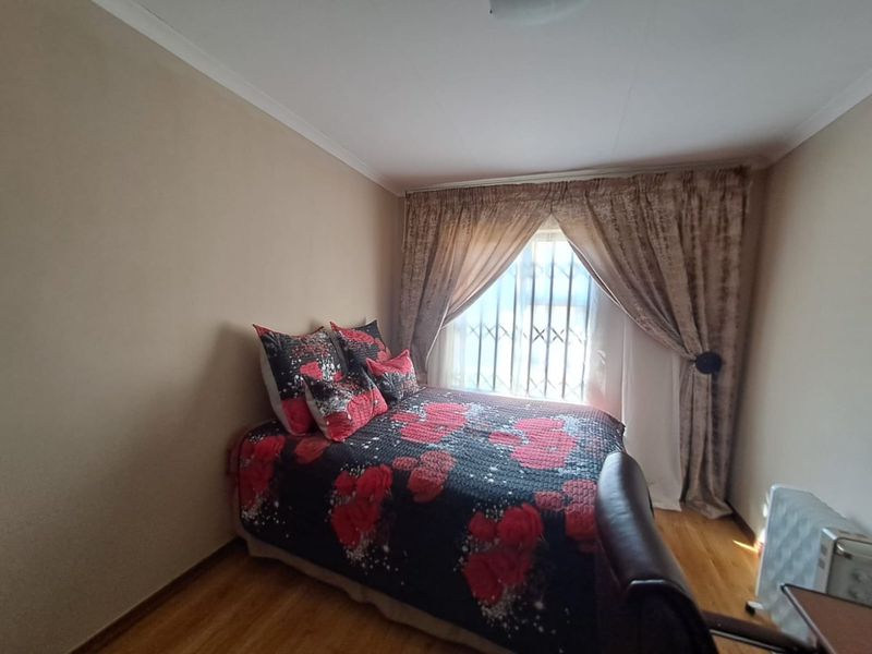 A bedroom featuring laminate flooring, a window with security bars, and cove cornice detailing.