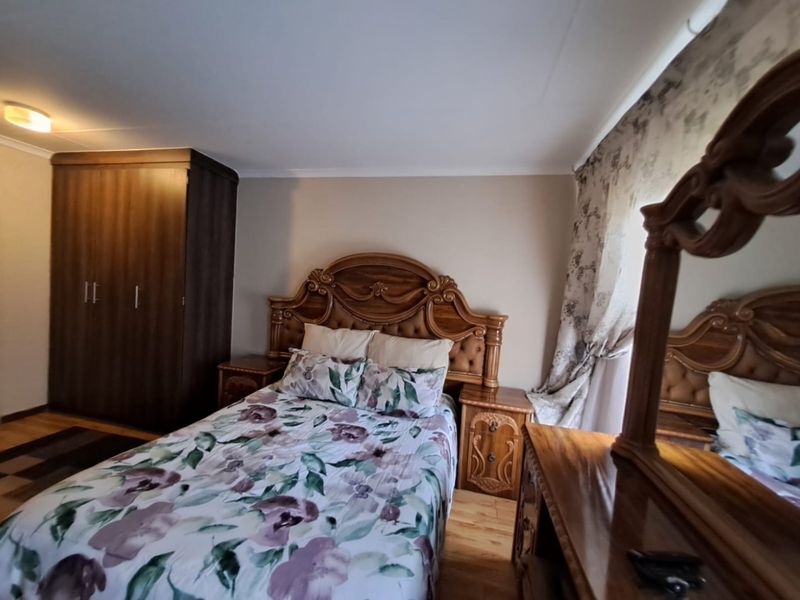 A well-proportioned bedroom featuring laminate flooring and a built-in wardrobe, offering a functional and comfortable living space.