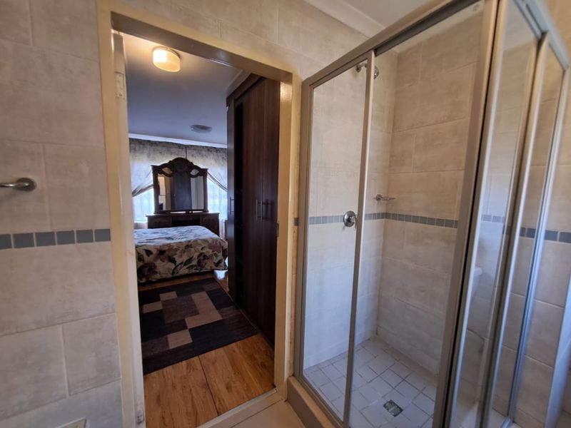 Bathroom featuring a glass-enclosed shower with tiled walls and flooring, providing direct access to the adjacent bedroom.