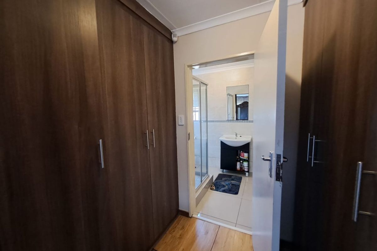 Bedroom featuring extensive built-in wooden cupboards, laminate flooring, and direct access to an en-suite bathroom.