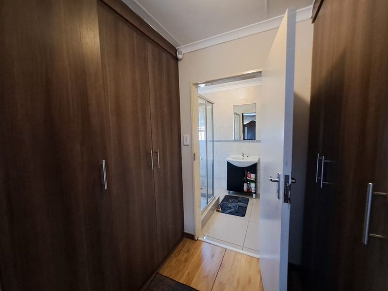Bedroom featuring extensive built-in wooden cupboards, laminate flooring, and direct access to an en-suite bathroom.