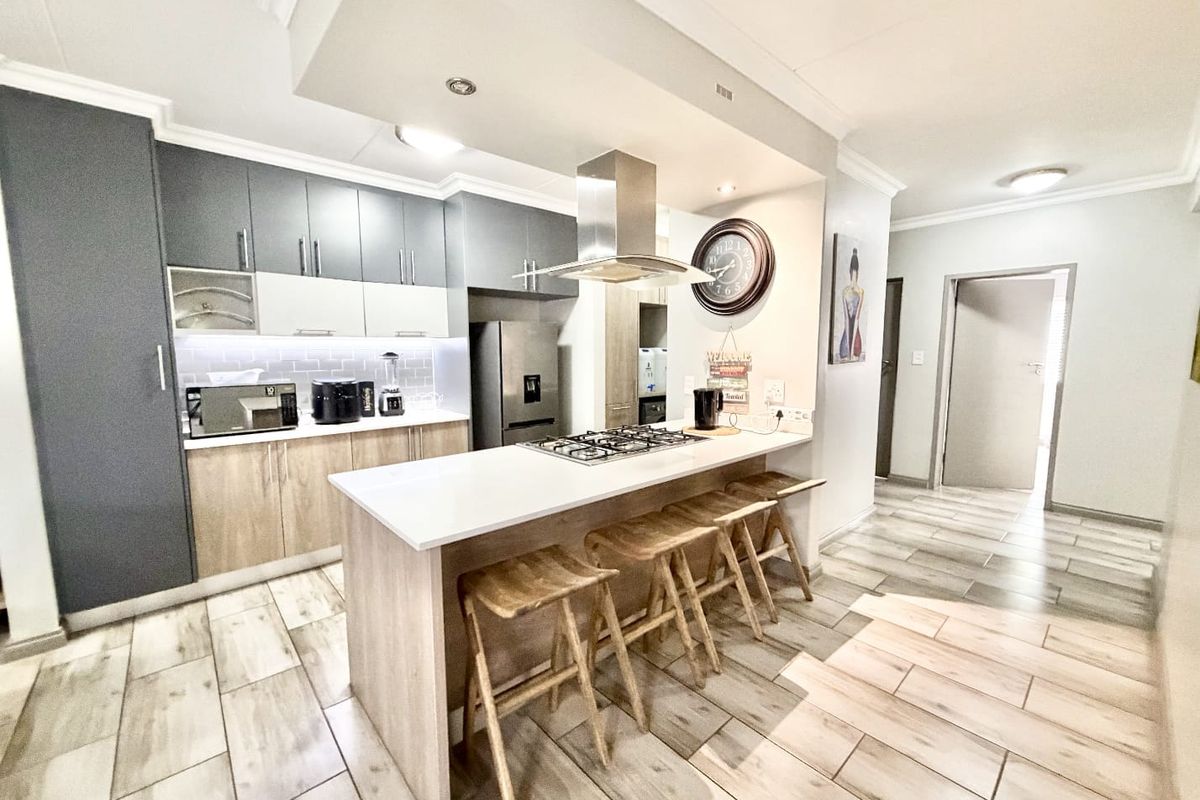 Modern kitchen featuring two-tone cabinetry, stone countertops, a central breakfast island with a gas hob, and integrated extractor fan.