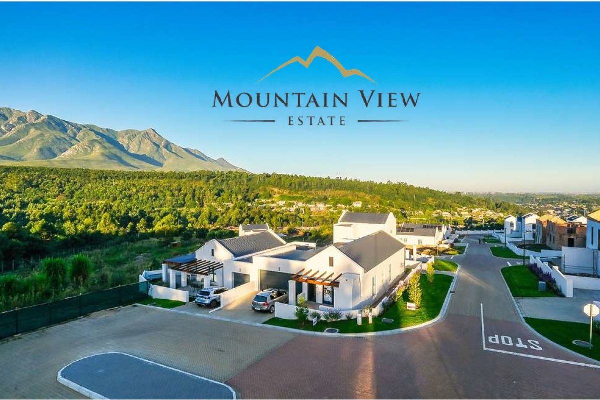 Aerial view of a modern residential estate featuring contemporary homes with pitched roofs, paved driveways, and scenic mountain views.