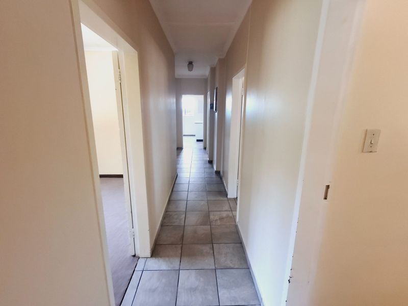 A clean, neutral-toned hallway featuring tiled flooring and access to multiple rooms, providing a functional transition space within the home.