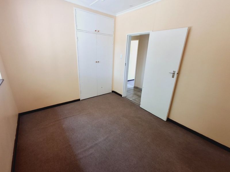 An empty bedroom featuring built-in cupboards, carpet flooring, and neutral wall paint, offering a blank canvas for potential updates.
