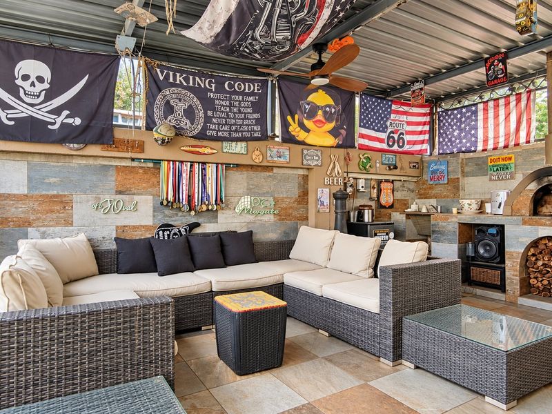 Covered outdoor patio featuring a built-in pizza oven, wood storage, tiled wall finishes, and durable floor tiling, ideal for entertainment.