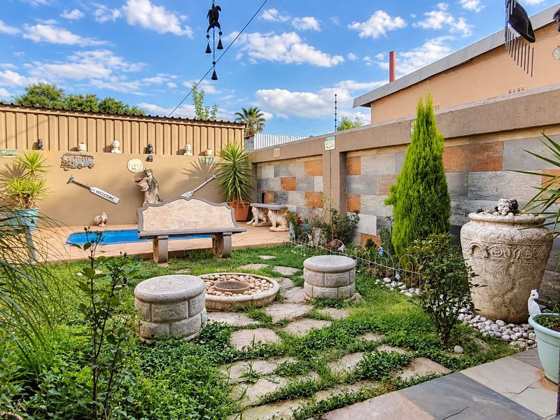 A well-maintained outdoor pool area featuring stone paving, a built-in stone bench, and decorative stone-clad boundary walls, creating a pleasant garden entertainment space.