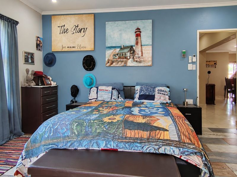 A well-maintained bedroom featuring tiled flooring, an air conditioning unit, and a blue accent wall, with an adjacent view into another living space.