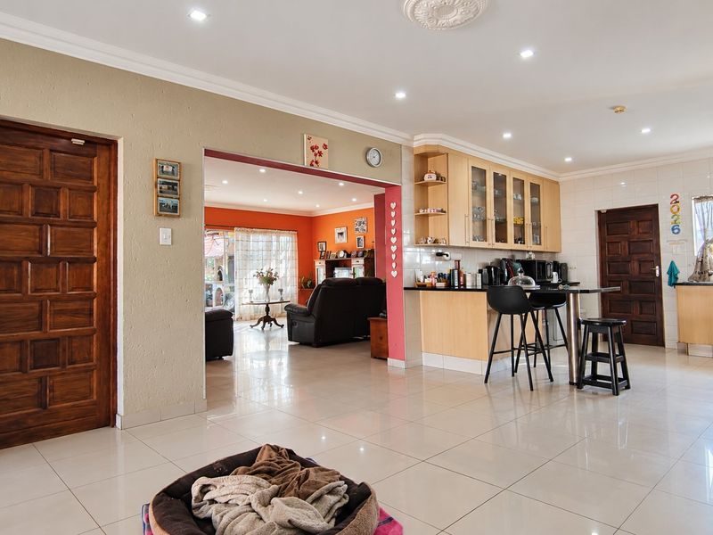 Spacious open-plan living area featuring a modern kitchen with breakfast bar, tiled flooring, and recessed lighting, seamlessly connecting to the adjacent living space.
