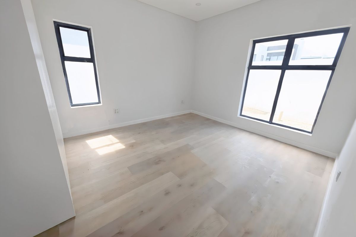 A bright, empty bedroom featuring light-toned engineered timber flooring, modern aluminium-framed windows, and clean white walls, ready for personalization.