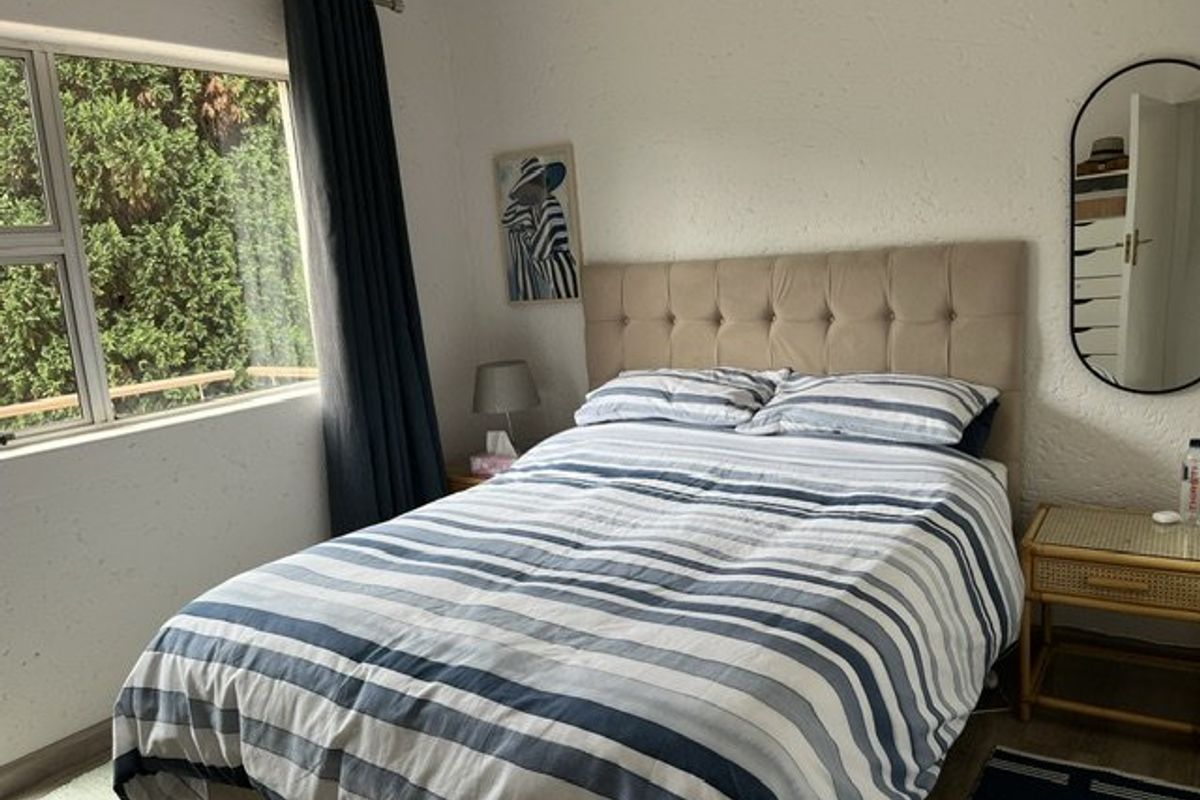 A cozy bedroom featuring a large window that allows for natural light and a textured wall finish.