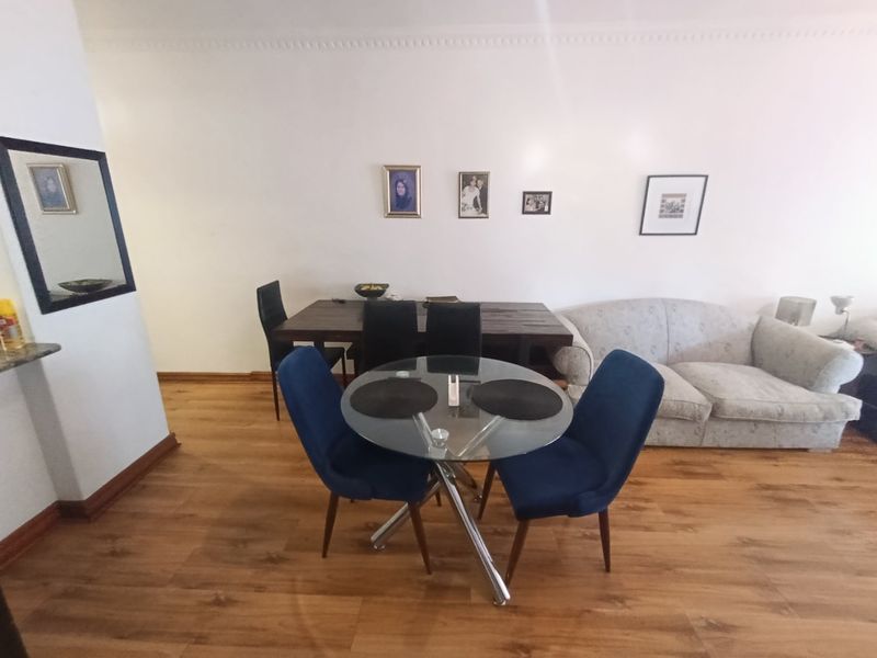 Open plan living and dining area featuring laminate flooring and decorative ceiling cornice.
