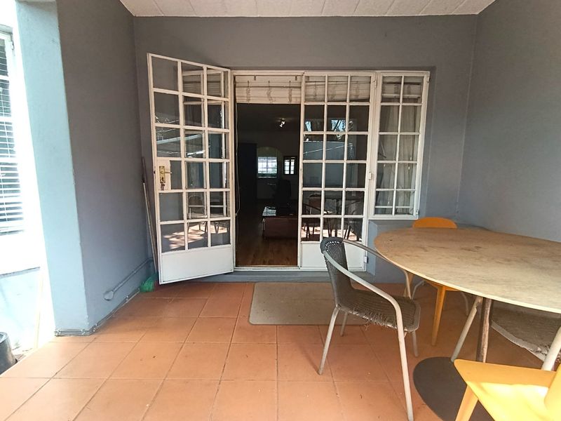 A covered patio area featuring tiled flooring and white-framed french doors providing access to the interior living space.