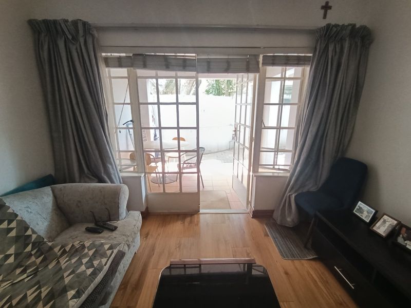 A living room featuring laminate flooring and classic french doors that open onto a private patio area.
