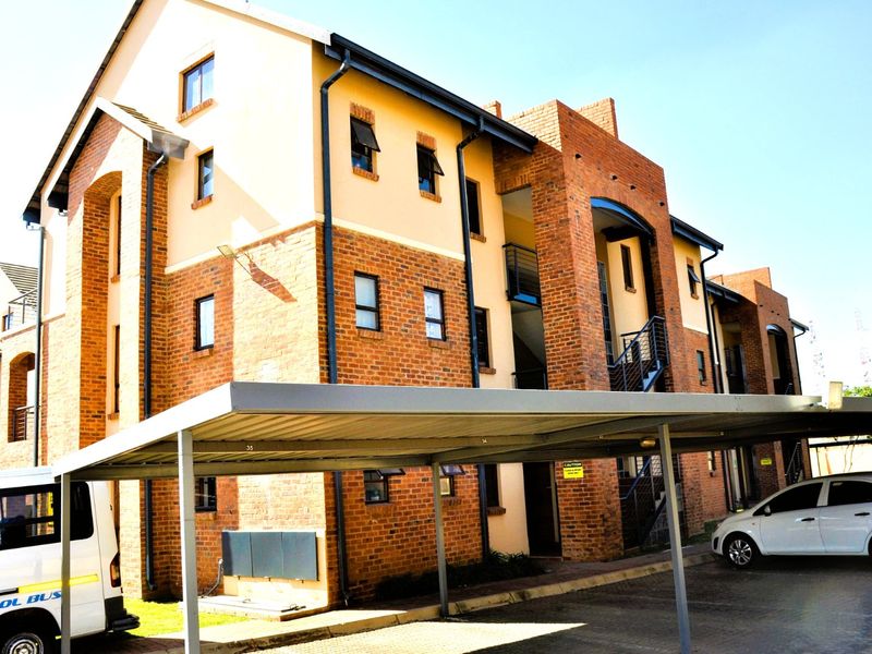 A multi-story residential building featuring a face brick facade, covered parking area, and external staircases.