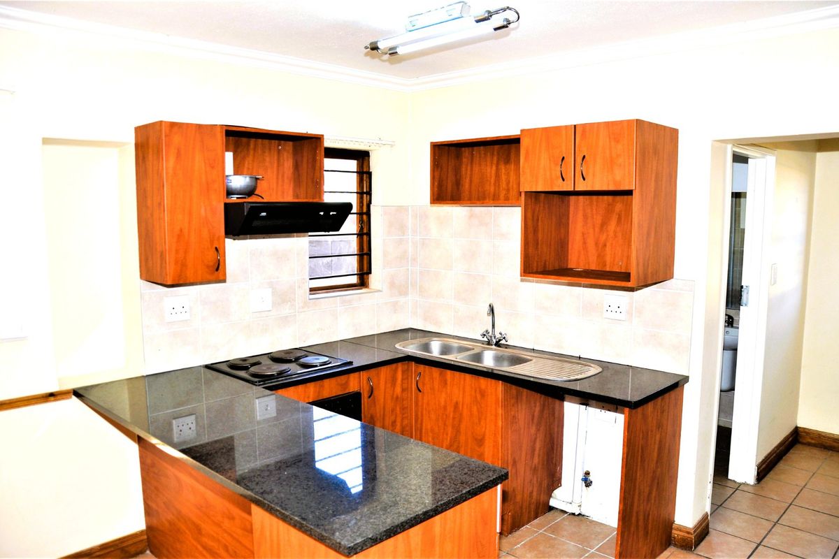 A functional kitchen featuring laminate cabinetry, granite countertops, a double bowl sink, and an electric hob with an extractor fan.