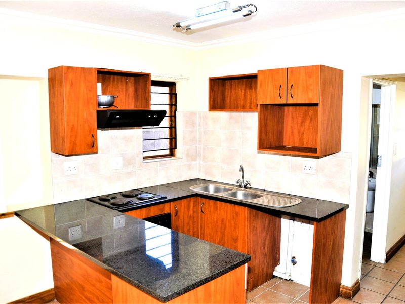 A functional kitchen featuring laminate cabinetry, granite countertops, a double bowl sink, and an electric hob with an extractor fan.